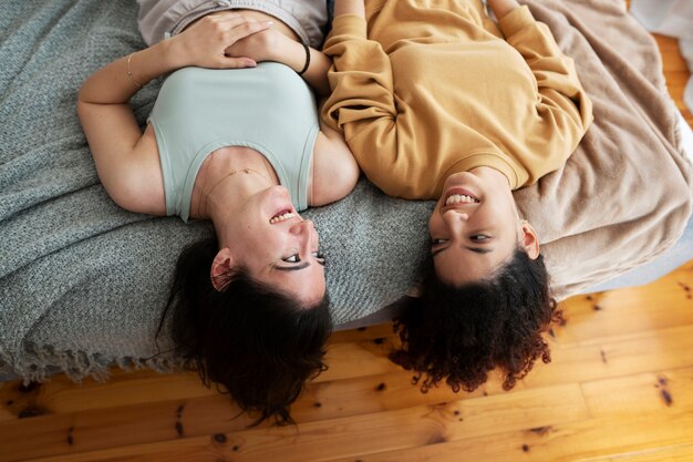 Mujeres sonrientes de alto ángulo acostadas en la cama