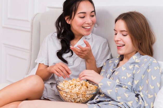 Mujeres sonrientes de alto ángulo comiendo palomitas de maíz