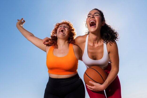 Mujeres sonrientes de ángulo bajo con pelota