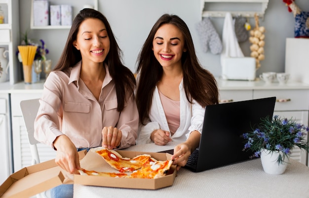 Mujeres sonrientes comiendo pizza después del trabajo