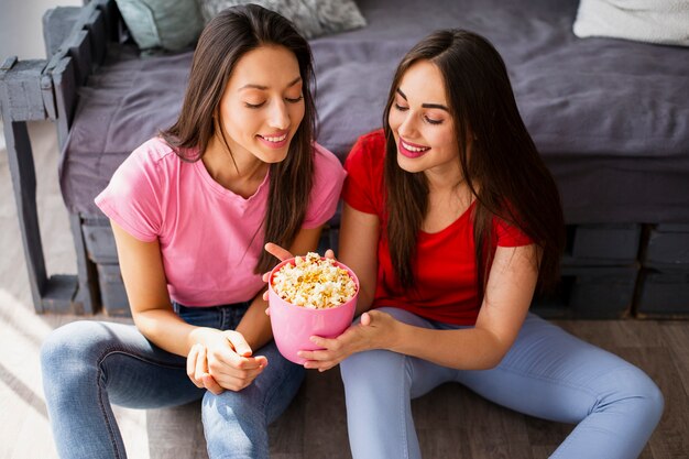 Mujeres sonrientes compartiendo palomitas de maíz