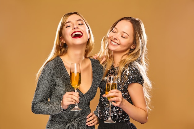 Mujeres sonrientes felices en elegantes vestidos glamorosos con copas de champán