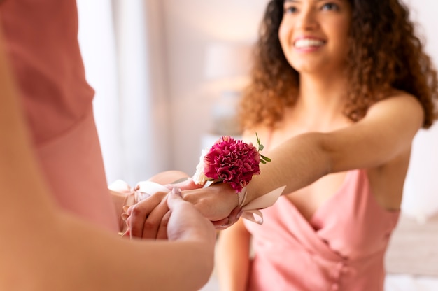 Mujeres sonrientes con flores en la fiesta nupcial de cerca