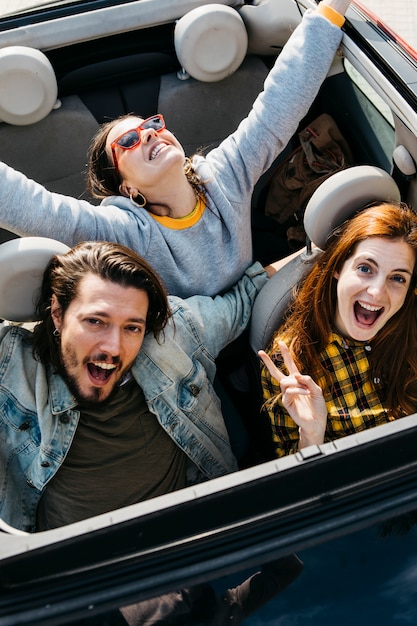 Mujeres sonrientes y hombre positivo sentado en coche