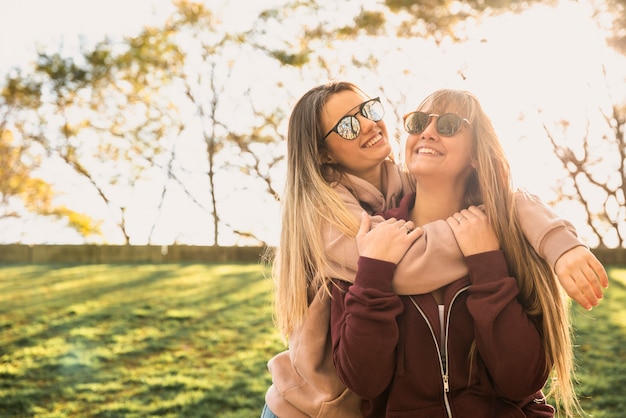 Foto gratuita mujeres sonrientes en la luz del sol abrazando