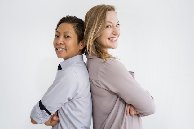 Mujeres sonrientes de pie espalda con espalda