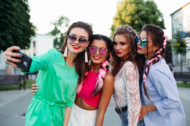 Mujeres sonrientes posando y clavando autorretratos en teléfonos inteligentes