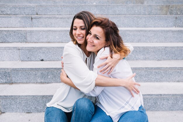 Mujeres sonrientes que abrazan en pasos