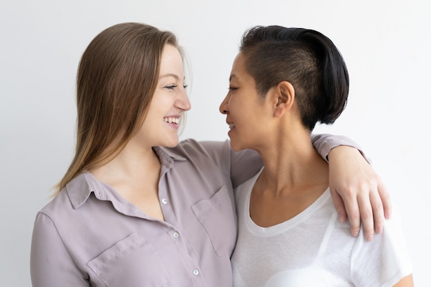 Mujeres sonrientes que abrazan y que se miran