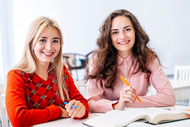 Mujeres sonrientes que estudian en biblioteca