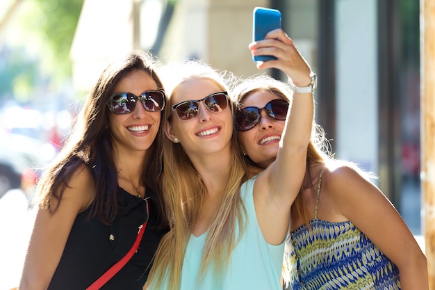 mujeres sonrientes que hacen autofoto en la calle