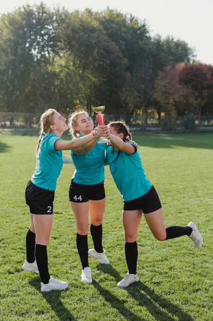 Mujeres sonrientes que sostienen un trofeo de fútbol