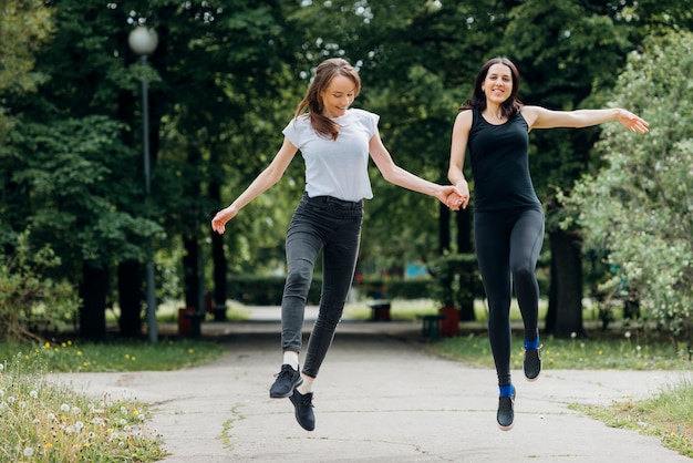 Mujeres sonrientes saltando y tomados de la mano