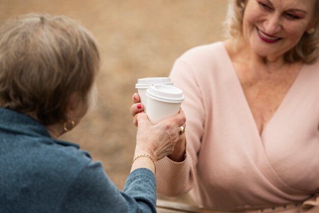 Mujeres sonrientes con tazas de café al aire libre