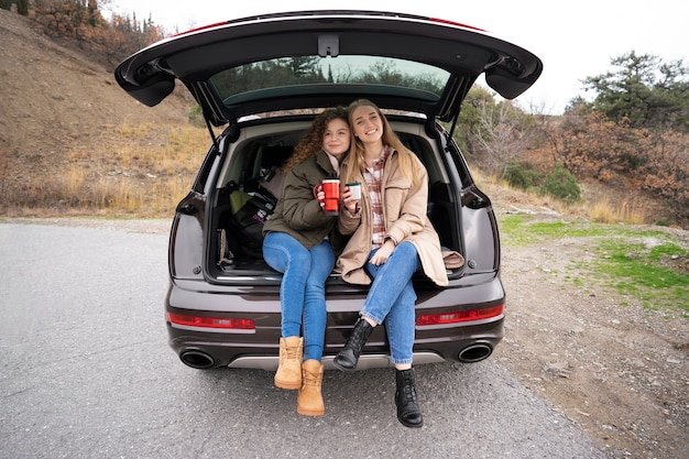 Mujeres sonrientes de tiro completo en el baúl del auto