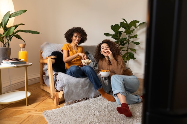 Foto gratuita mujeres sonrientes de tiro completo en casa