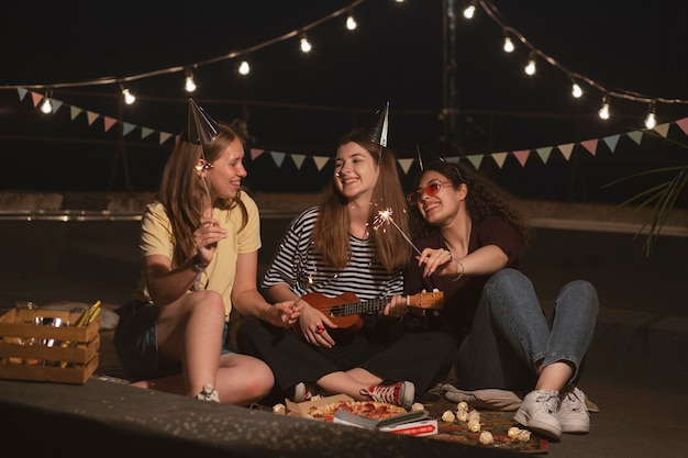 Mujeres sonrientes de tiro completo con fuegos artificiales