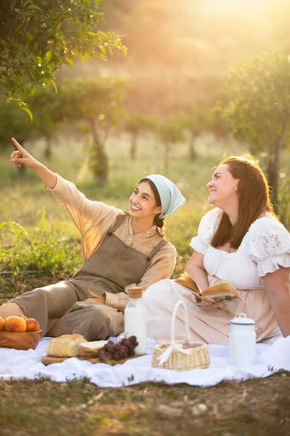 Foto gratuita mujeres sonrientes de tiro completo en picnic