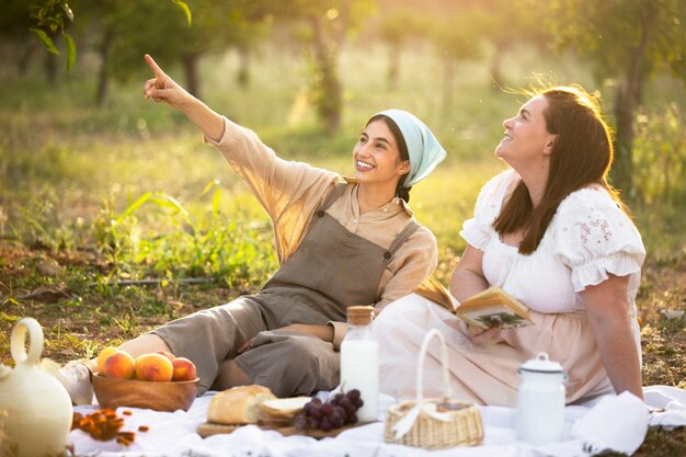 Mujeres sonrientes de tiro completo en picnic