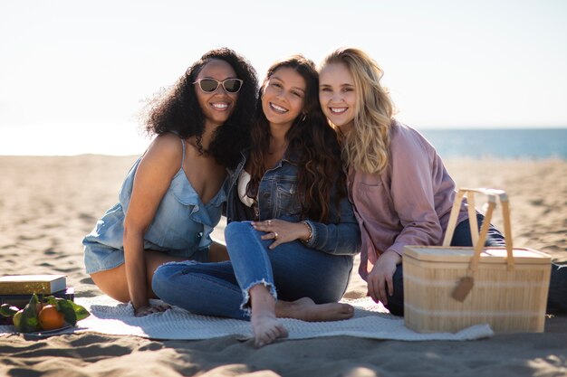 Mujeres sonrientes de tiro completo en la playa