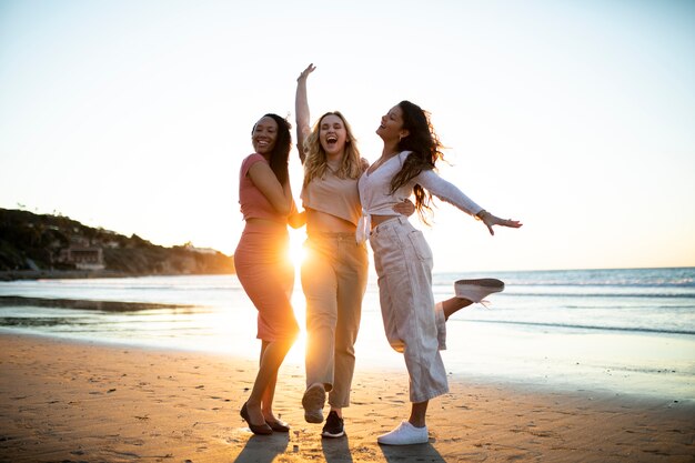 Mujeres sonrientes de tiro completo en la playa