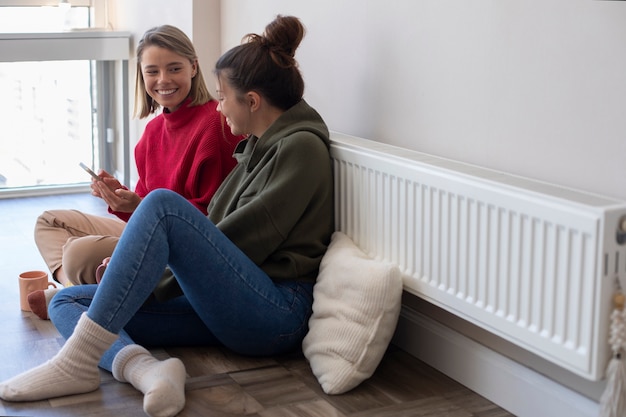 Foto gratuita mujeres sonrientes de tiro completo con teléfono inteligente