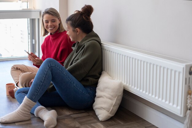 Mujeres sonrientes de tiro completo con teléfono inteligente