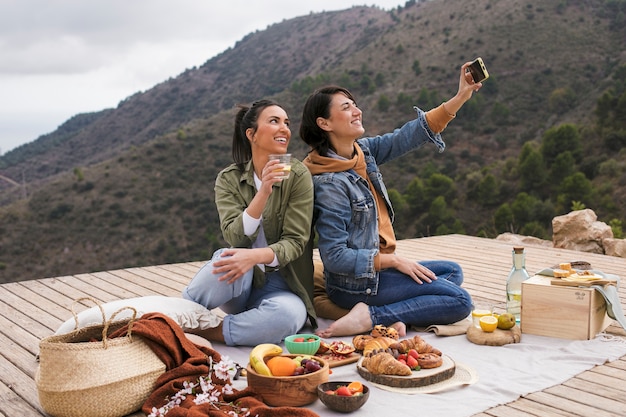 Foto gratuita mujeres sonrientes de tiro completo tomando selfie