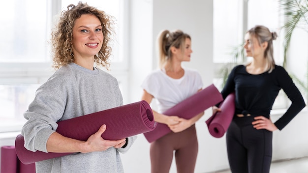 Mujeres sonrientes de tiro medio con colchonetas de yoga