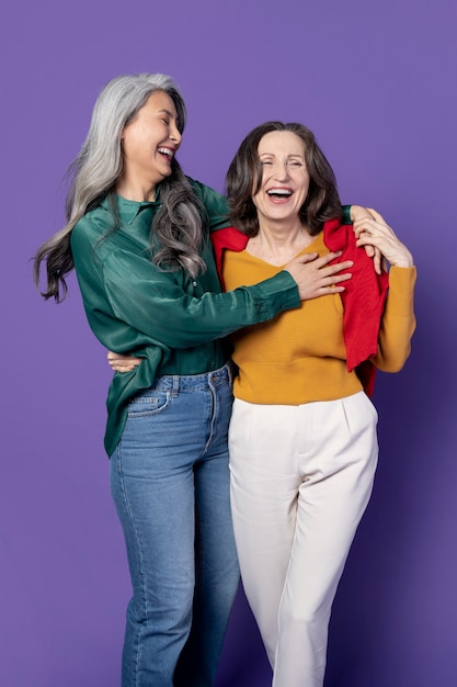 Foto gratuita mujeres sonrientes de tiro medio con fondo morado