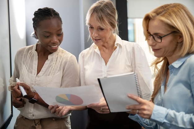 Mujeres sonrientes de tiro medio haciendo un plan de negocios