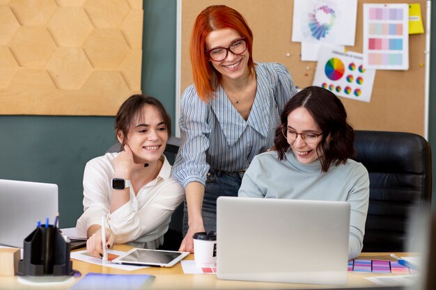 Mujeres sonrientes de tiro medio en la oficina