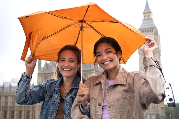 Foto gratuita mujeres sonrientes de tiro medio con paraguas