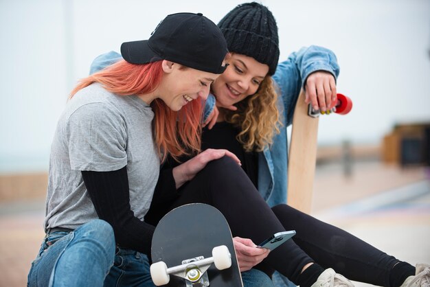 Mujeres sonrientes de tiro medio con patinetas