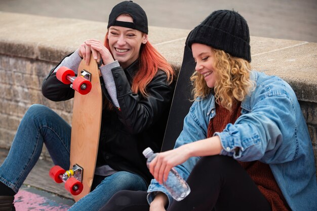 Mujeres sonrientes de tiro medio con patinetas