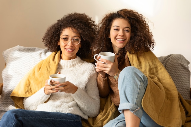 Foto gratuita mujeres sonrientes de tiro medio sentadas en el sofá