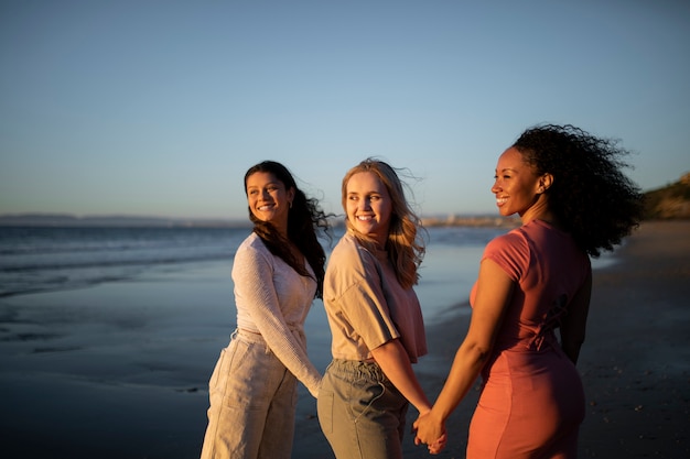 Mujeres sonrientes de tiro medio tomados de la mano