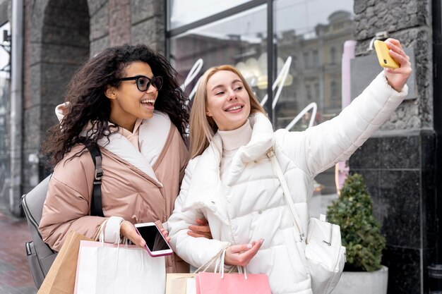 Mujeres sonrientes de tiro medio tomando selfie