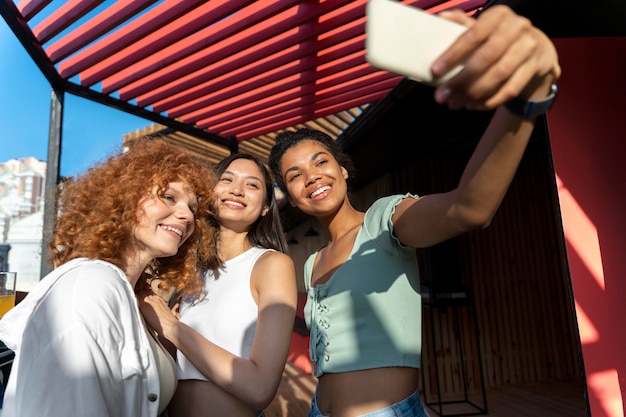 Foto gratuita mujeres sonrientes de tiro medio tomando selfie