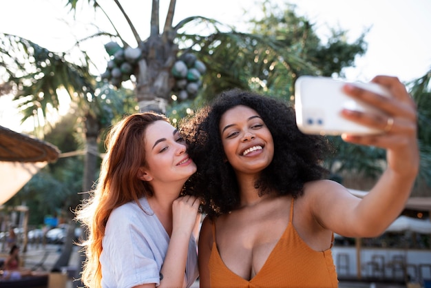 Foto gratuita mujeres sonrientes de tiro medio tomando selfie