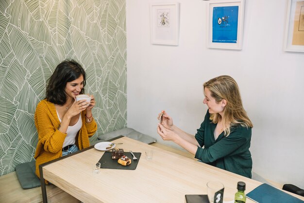 Mujeres sonrientes tomando fotos en la cafetería