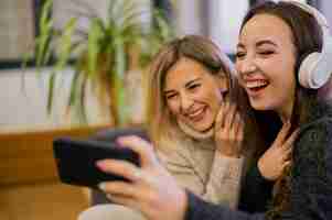Foto gratuita mujeres sonrientes tomando selfie con auriculares