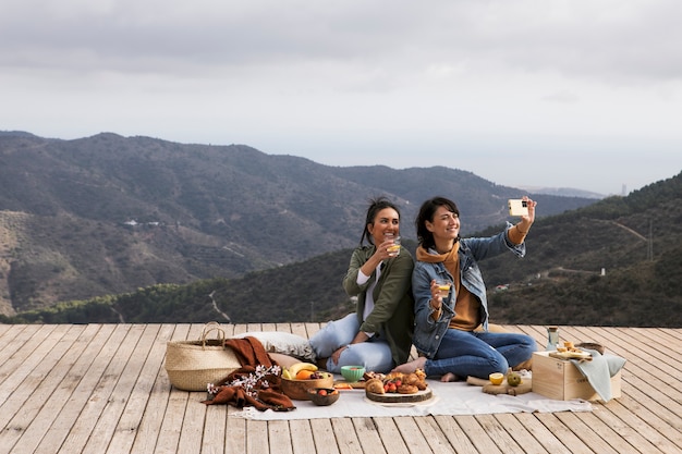 Mujeres sonrientes tomando selfie tiro completo