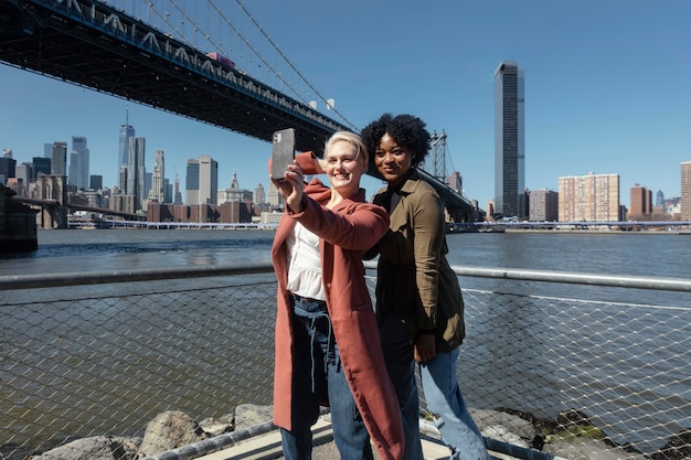 Mujeres sonrientes tomando selfie tiro medio