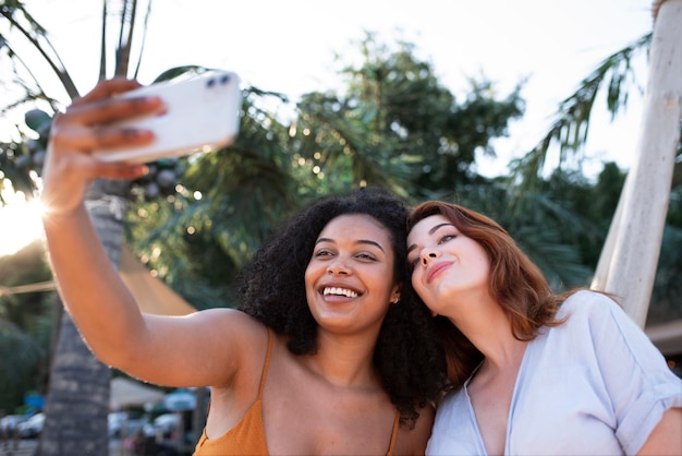 Mujeres sonrientes tomando selfie tiro medio