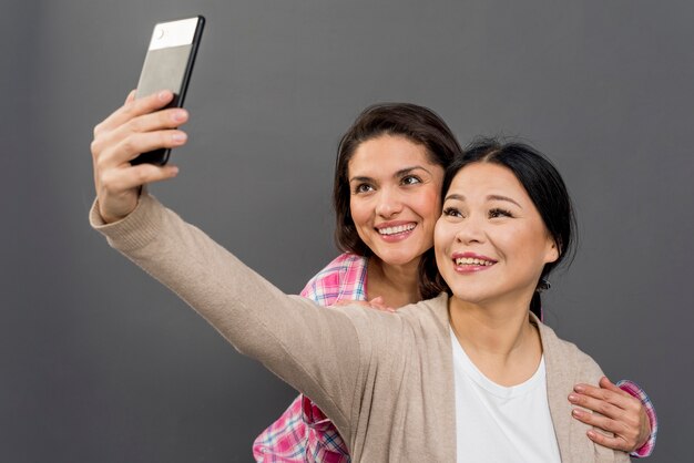 Mujeres sonrientes tomando selfies