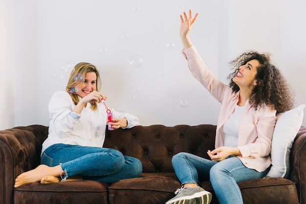 Foto gratuita mujeres soplando burbujas en el sofá