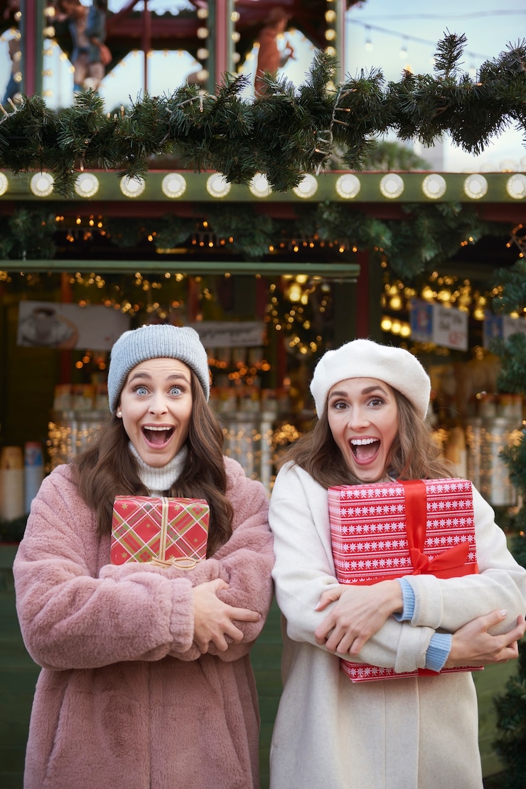 Foto gratuito mujeres sorprendidas con regalos de navidad en el mercado de navidad