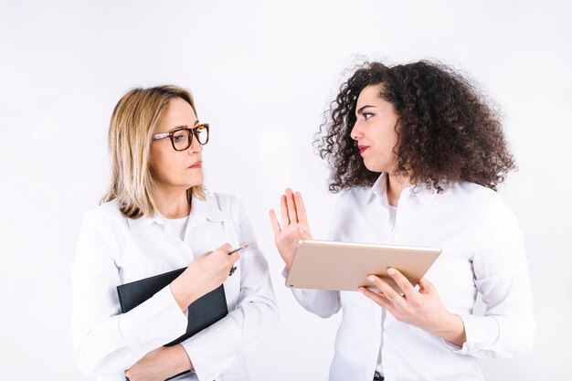 Mujeres con tableta y portátil discutiendo problema