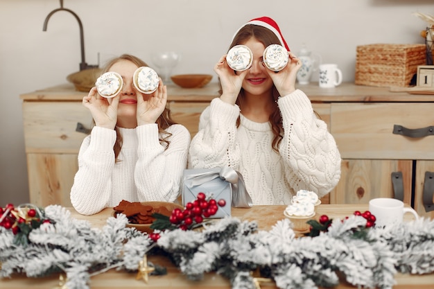 Foto gratuita las mujeres tienen cupcakes. amigos en una decoración navideña. chica con sombrero de santa.